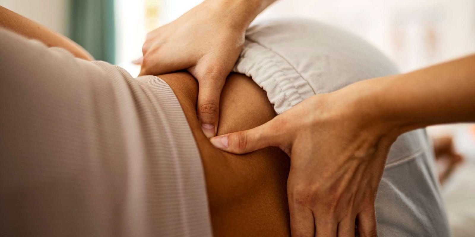 Osteopathie: Hände einer Osteopathin berühren den Rücken einer Patientin.