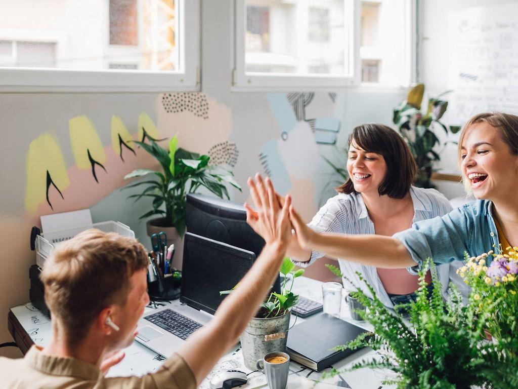 Bild: Kollege und Kollegin geben sich High-Five im Büro und lachen