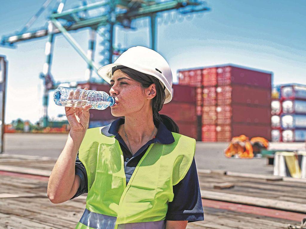 Symbolbild Hitze: Arbeiterin im Hafen trinkt eine Flasche Wasser