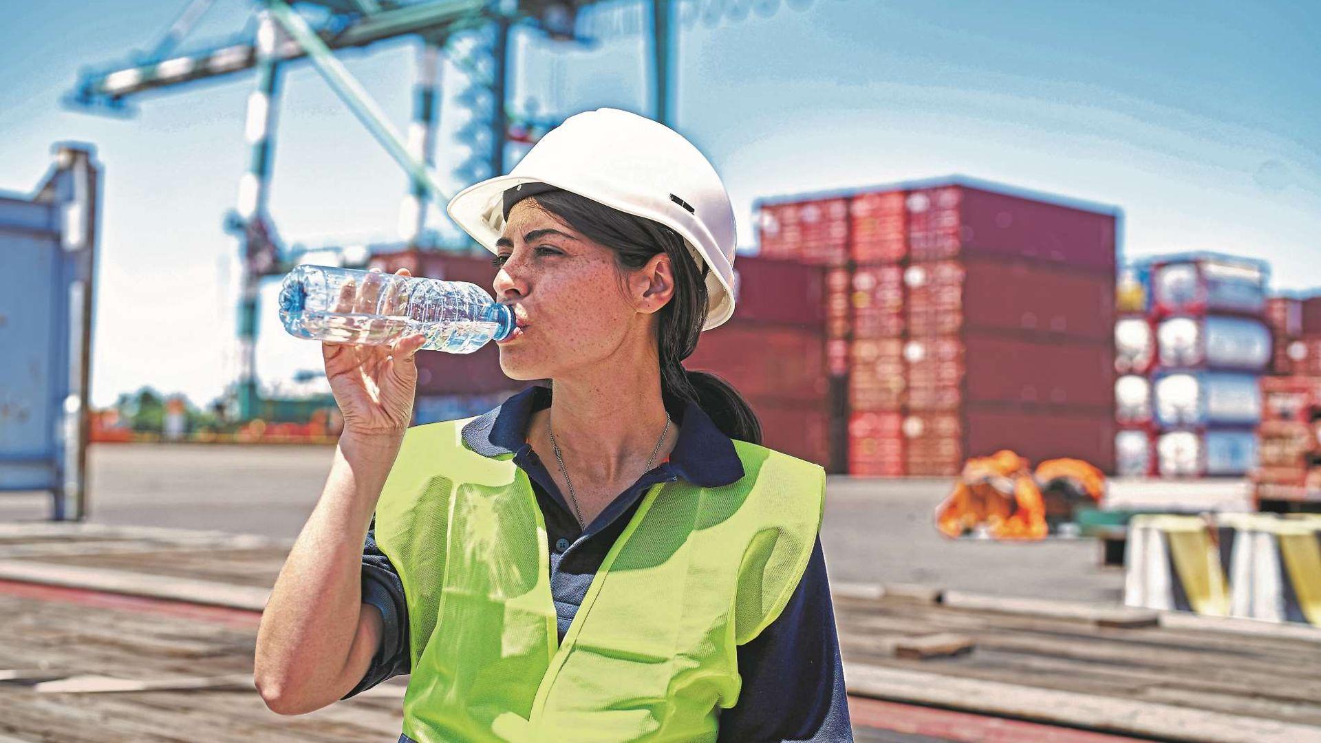 Symbolbild Hitze: Arbeiterin im Hafen trinkt eine Flasche Wasser