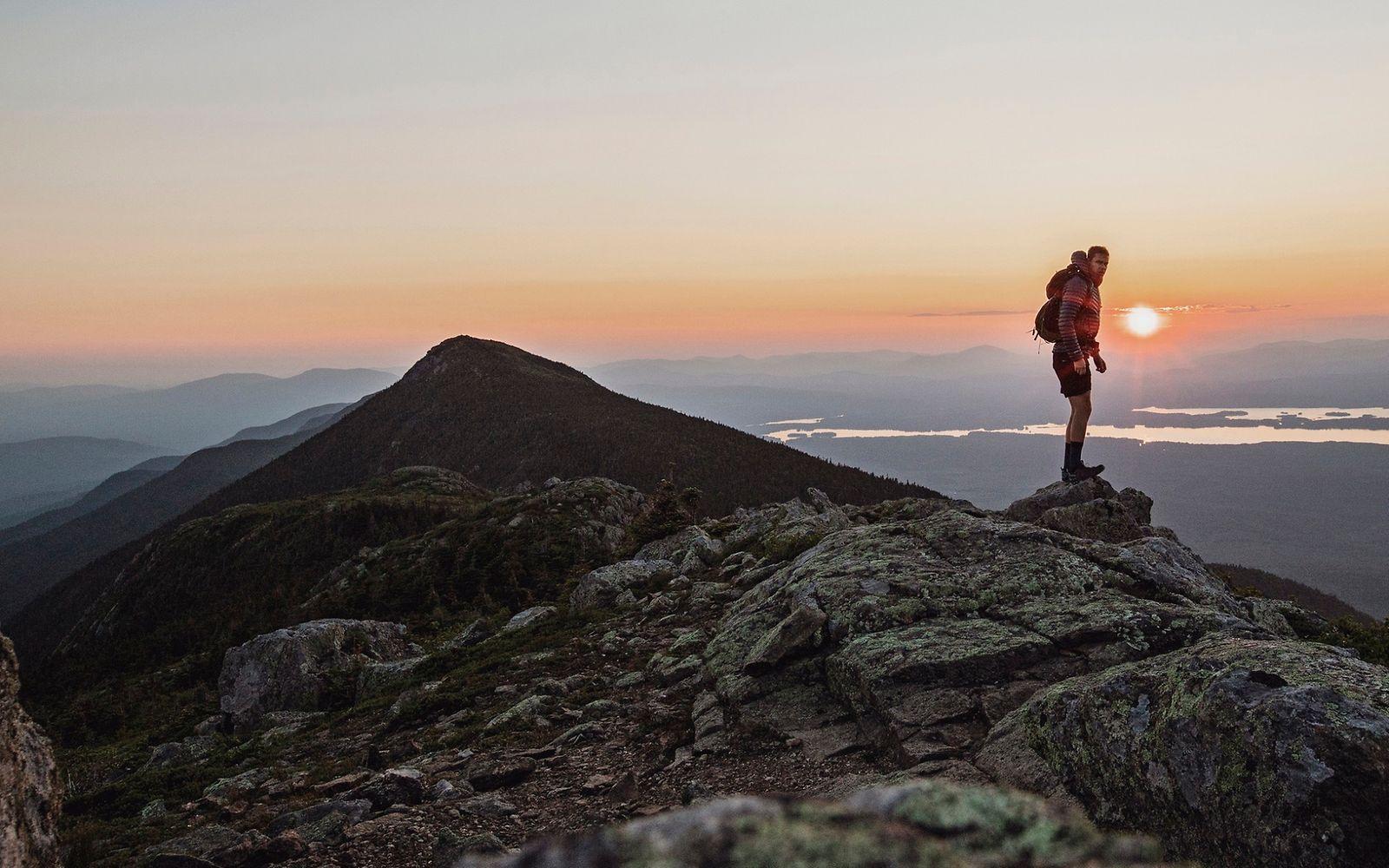 Sabbatical: Mann steht bei Sonnenuntergang auf einem Berg