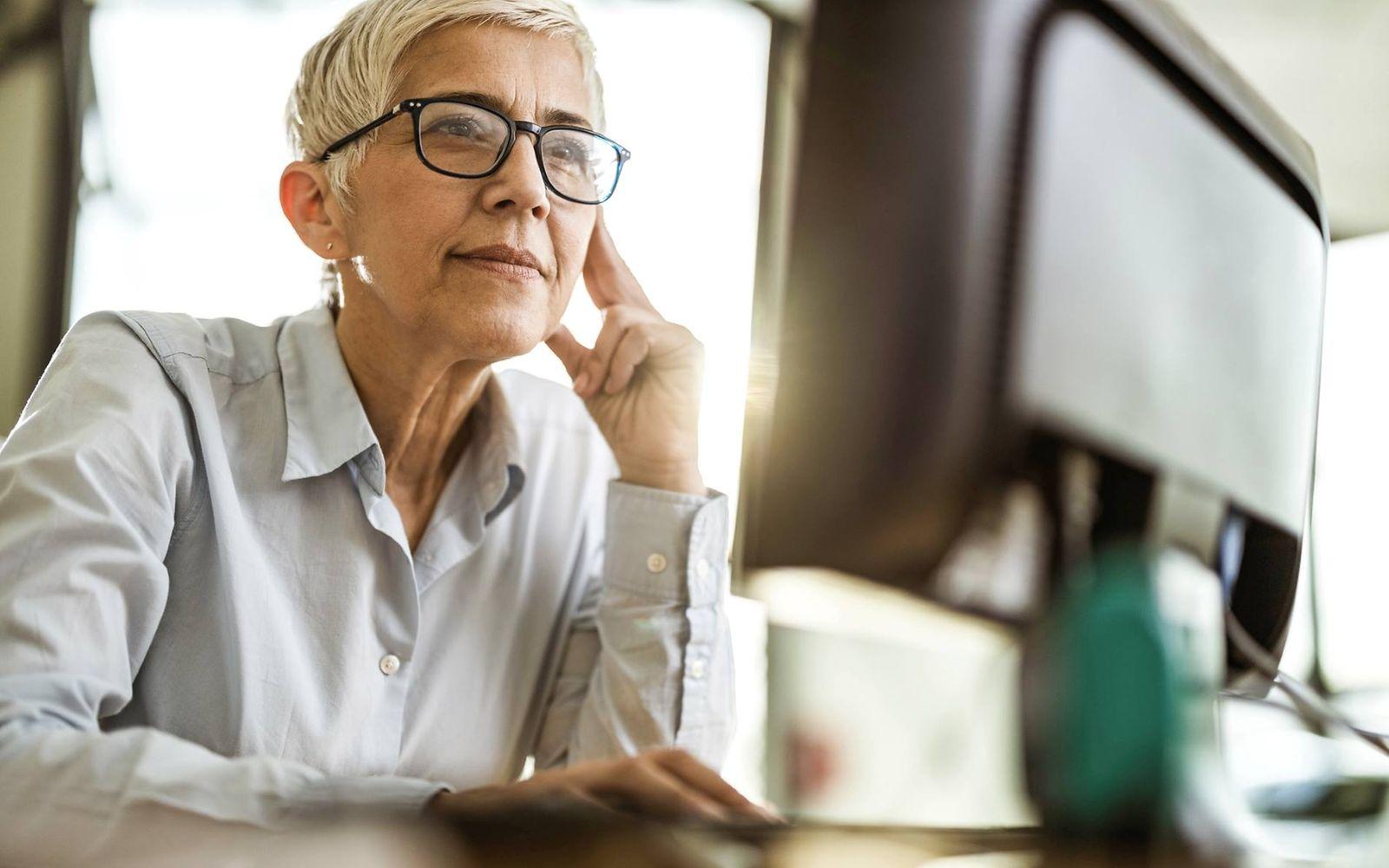 Bild: Frau mit Brille schaut etwas auf einem Computerbildschirm nach