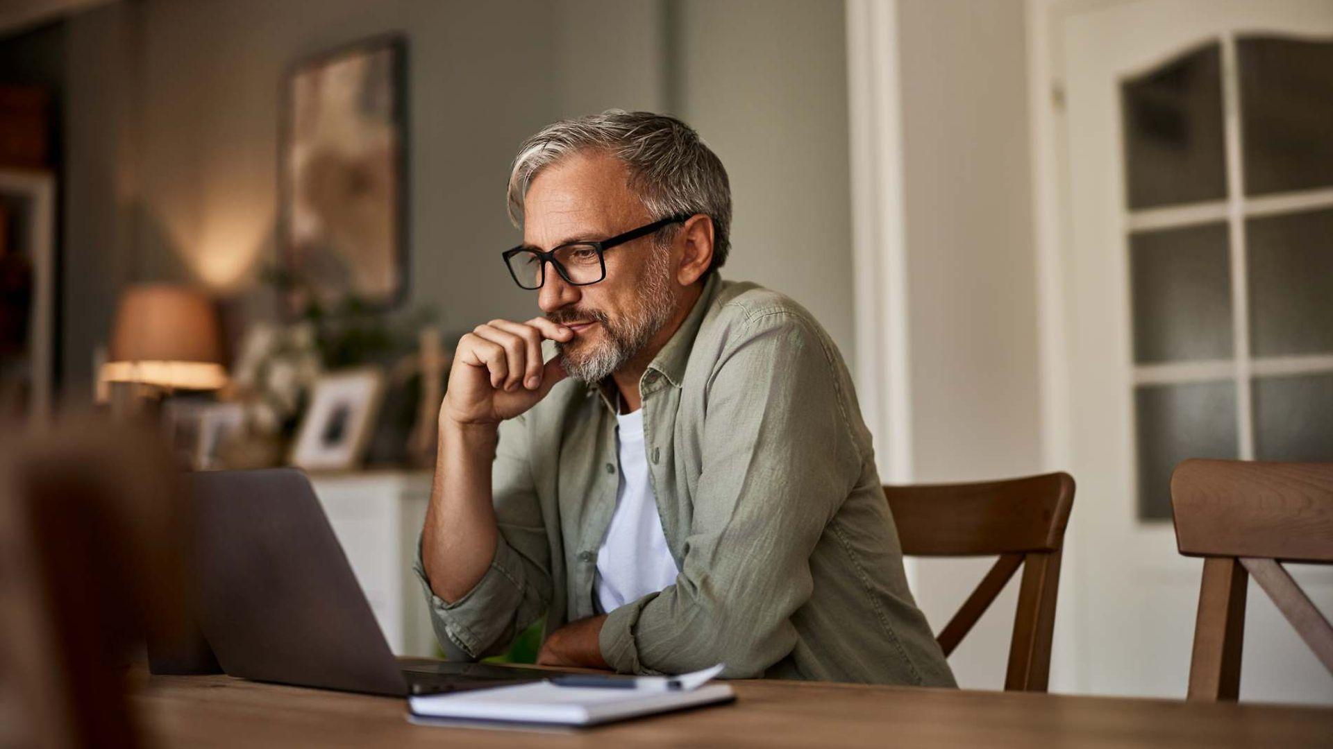 Bild: Mann mit Brille liest etwas am Laptop
