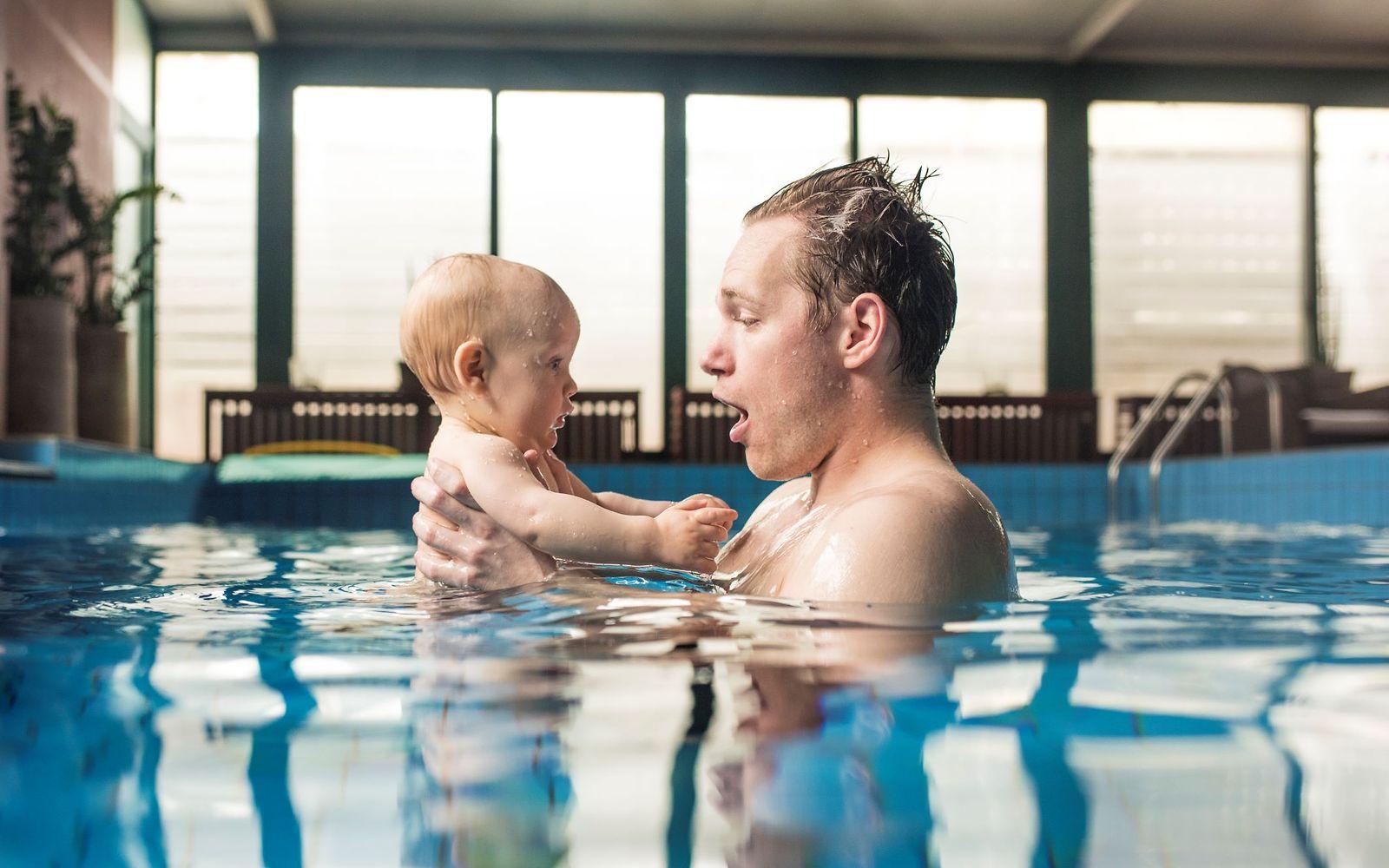 Symbolbild: Junger Papa mit Baby im Schwimmbad