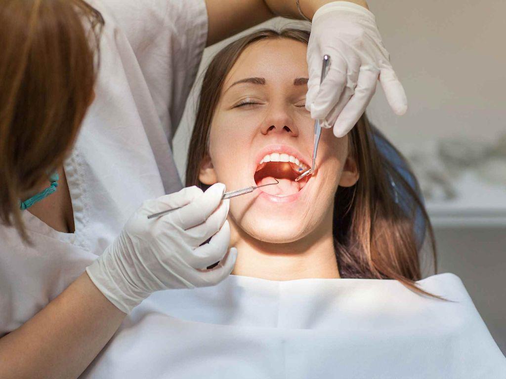Frau mit offenem Mund während einer Zahnarztbehandlung.