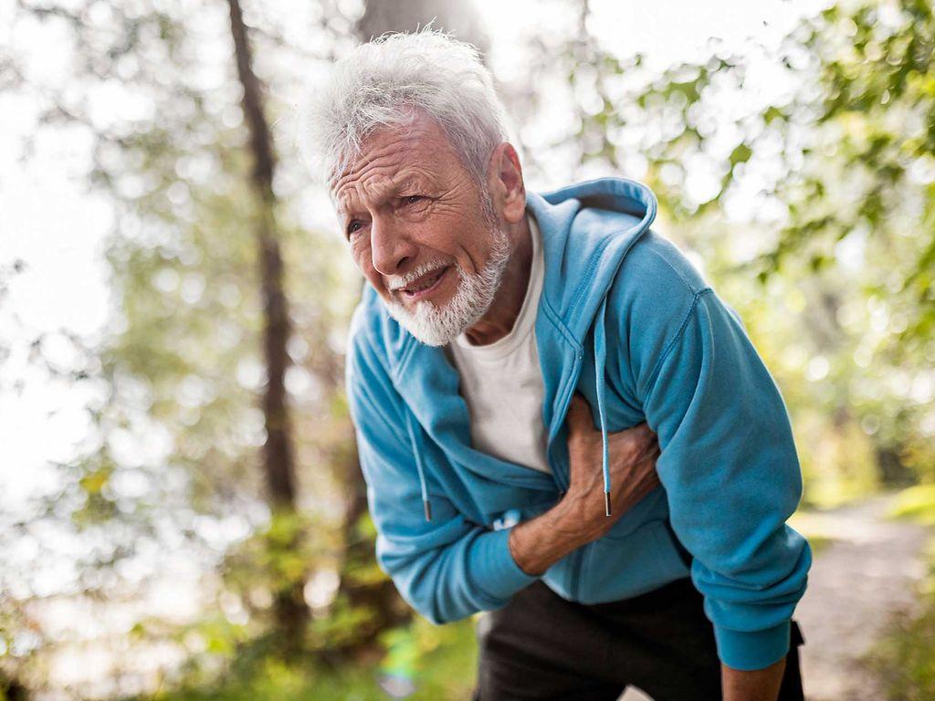 Angina Pectoris: Mann mit schmerzverzerrtem Gesicht greift sich an die Brust