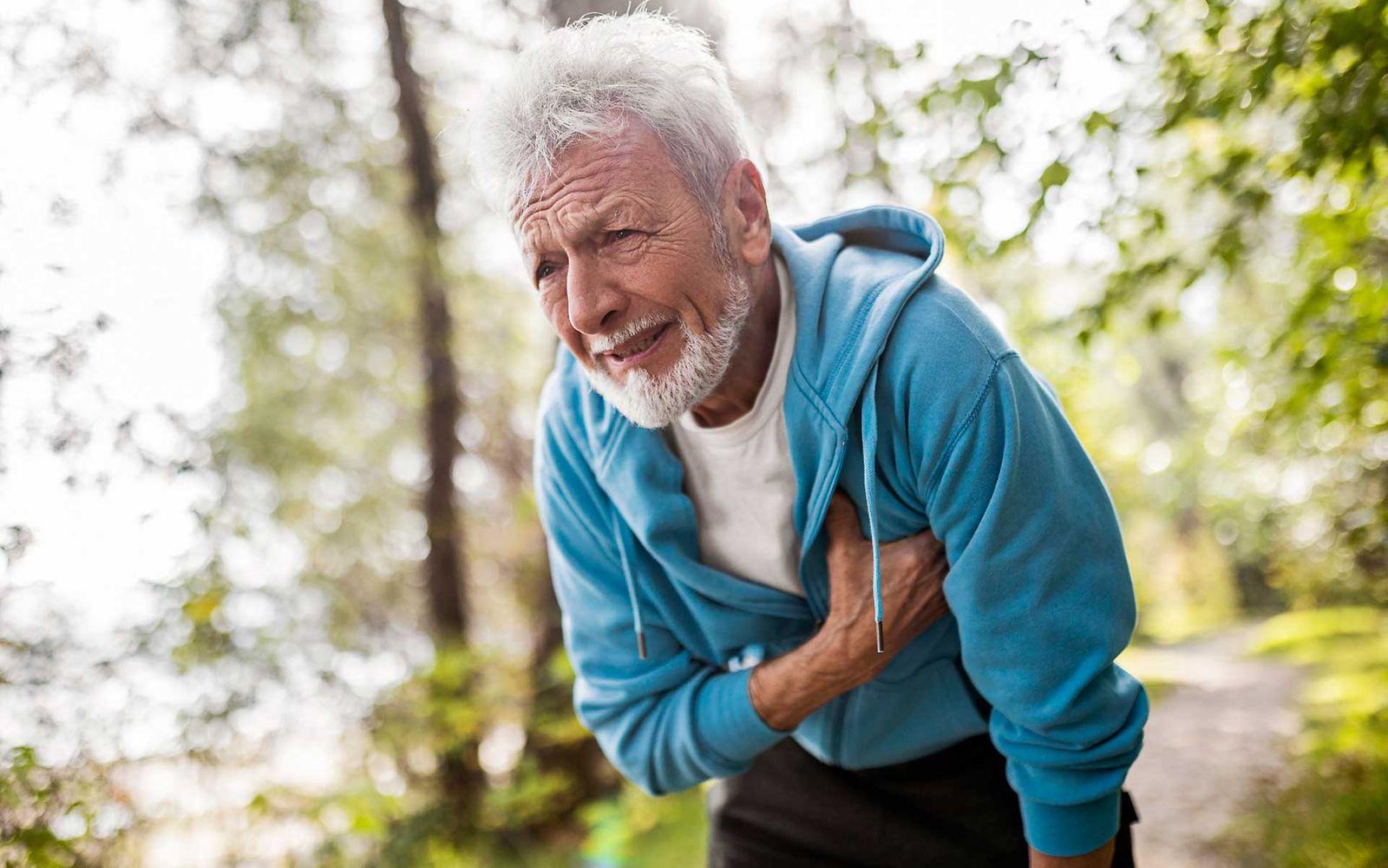 Angina Pectoris: Mann mit schmerzverzerrtem Gesicht greift sich an die Brust