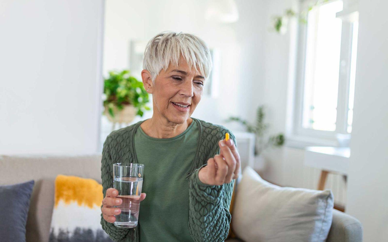 Symbolbild Osteoporose-Behandlung: Frau nimmt Tablette ein