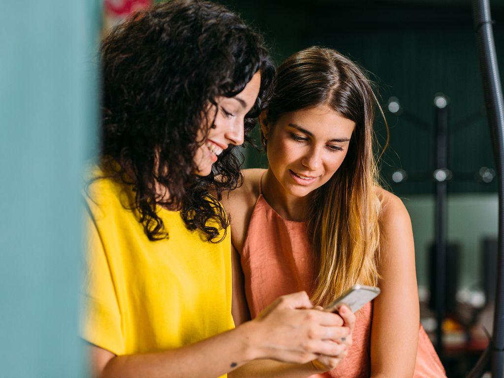 Two young women checking apps.