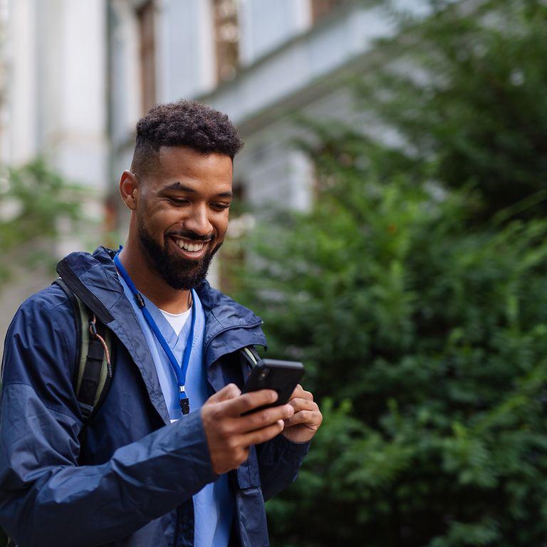 DAK App: Man outdoors in street using a phone, smiling.