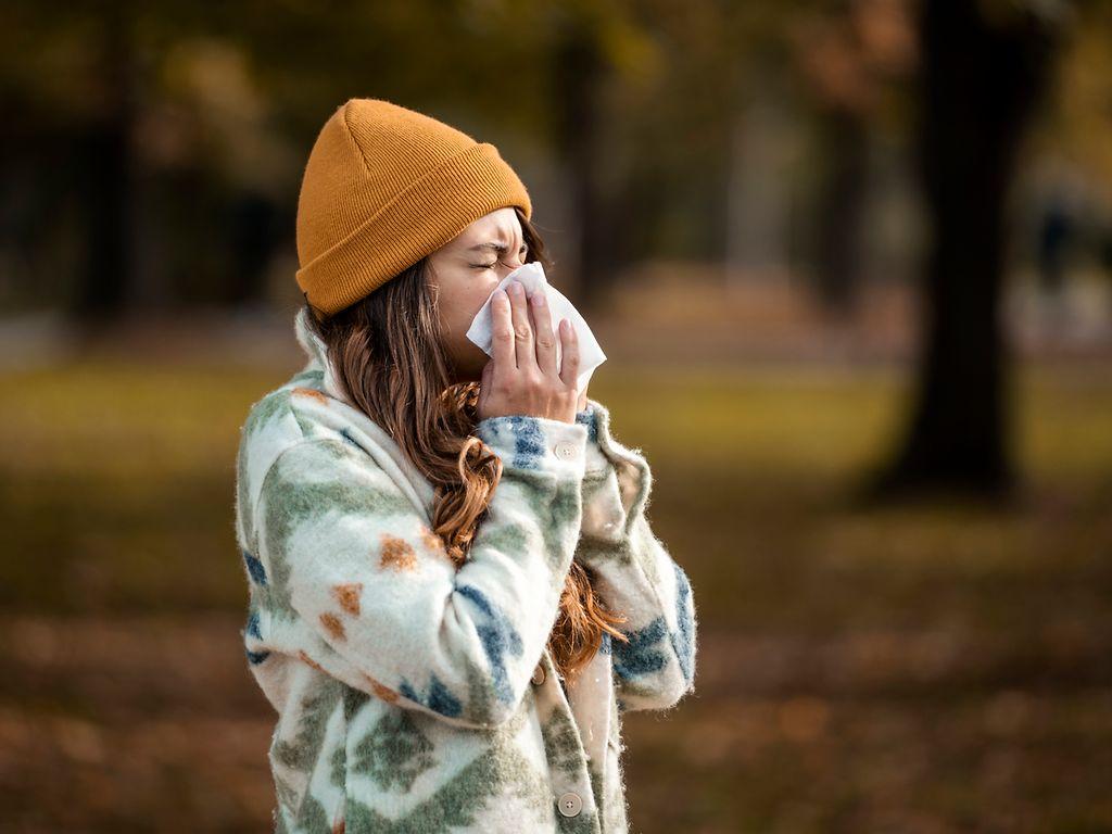 Woman sneezing in handkerchief at autumn.