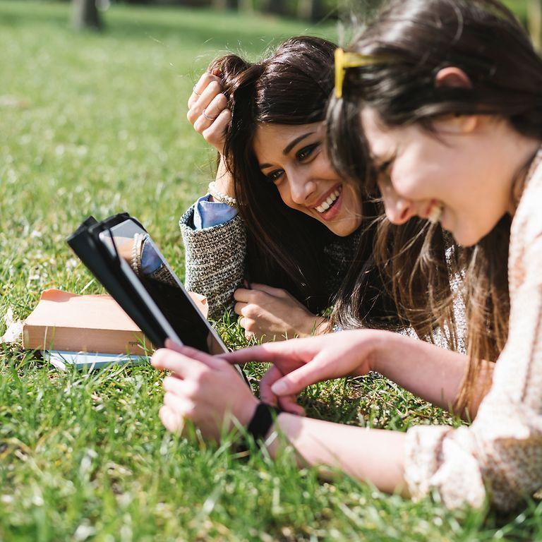 Young students using a tablet in the park.