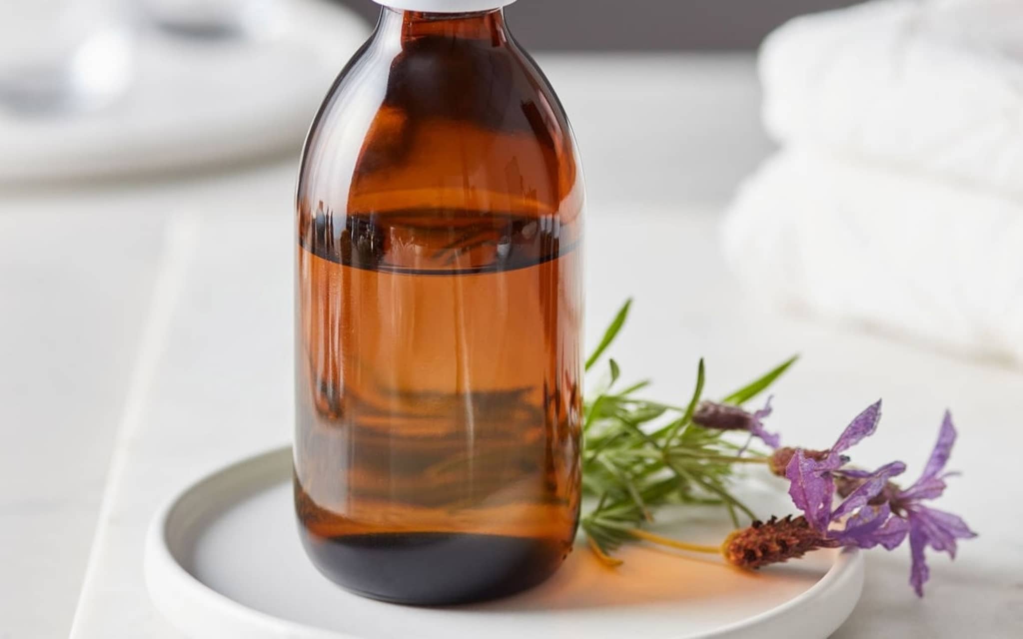 Homöopathie: Fläschchen mit homöopathischer Flüssigkeit steht neben einer Blume auf einem Tablett