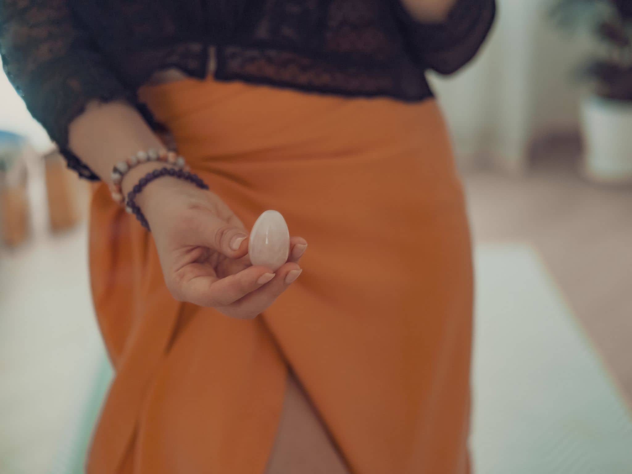 Yoni Ei: Eine Frau hält ein Yoni-Ei aus Rosenquarz in der Hand