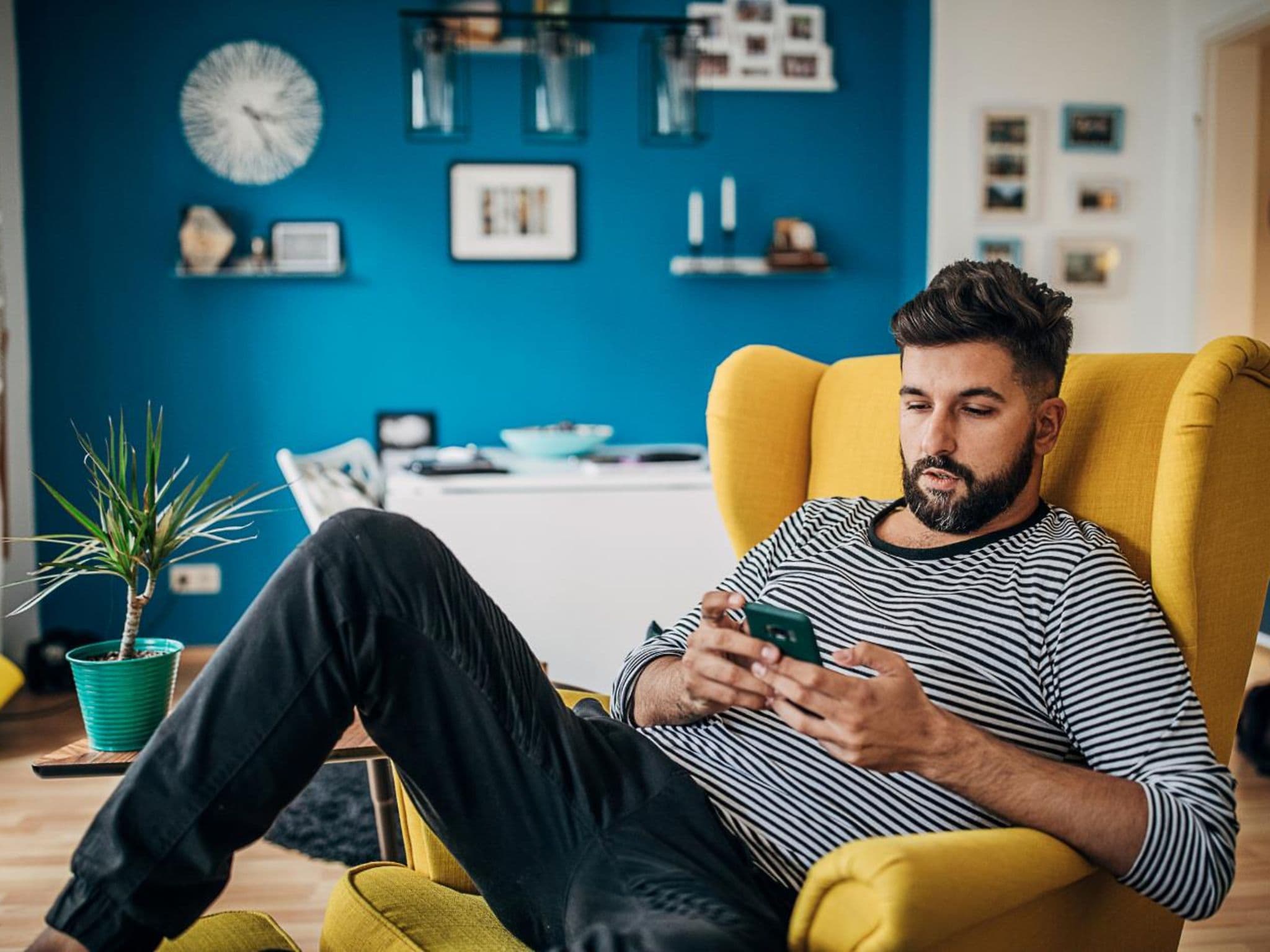 DAK App: Man is sitting in a chair and casually using his smartphone.