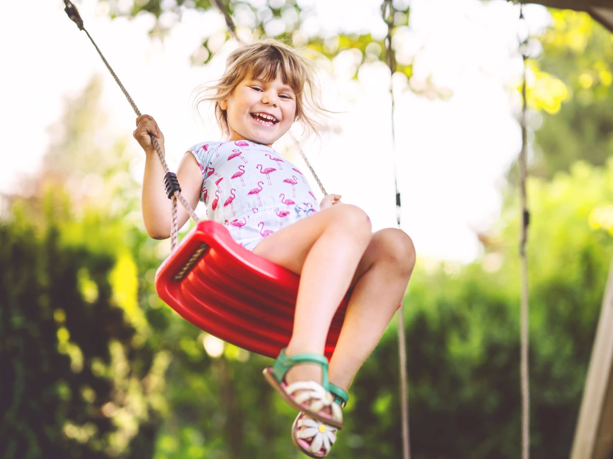 Resilienz bei Kindern: Ein kleines Mädchen schaukelt und lächelt glücklich