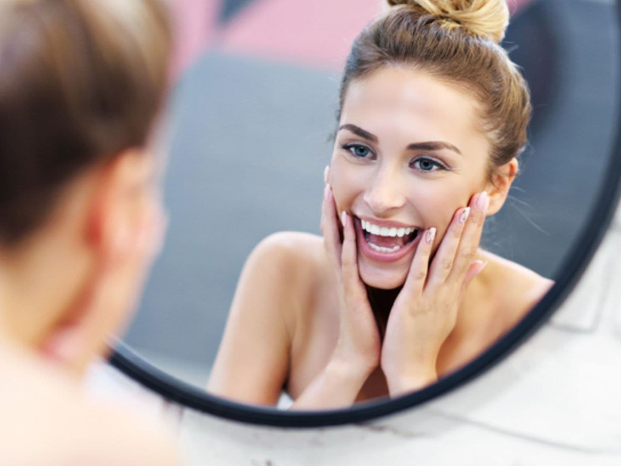 Selbstliebe: Eine junge Frau lacht in den Spiegel.