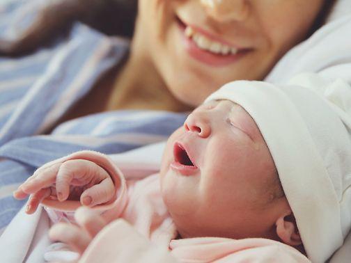 Checkliste Baby: Frau und Baby liegen nebeneinander