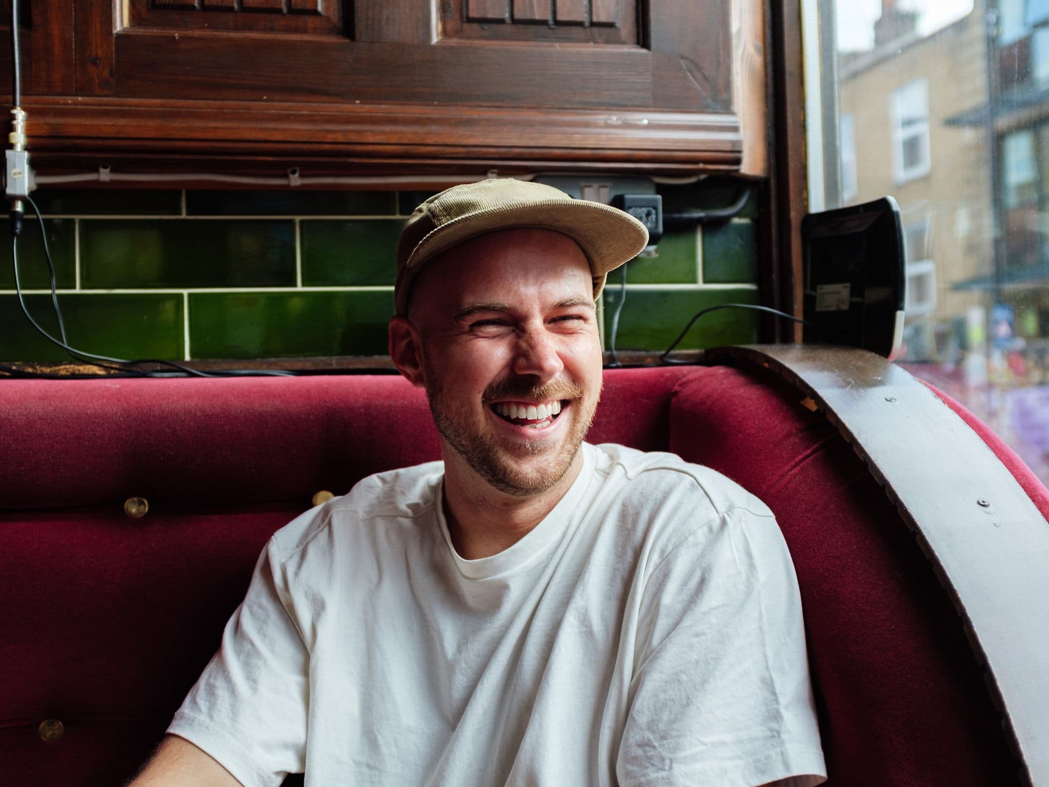 Penis stimulieren: Ein junger Mann sitzt auf einem Sofa und lächelt zufrieden