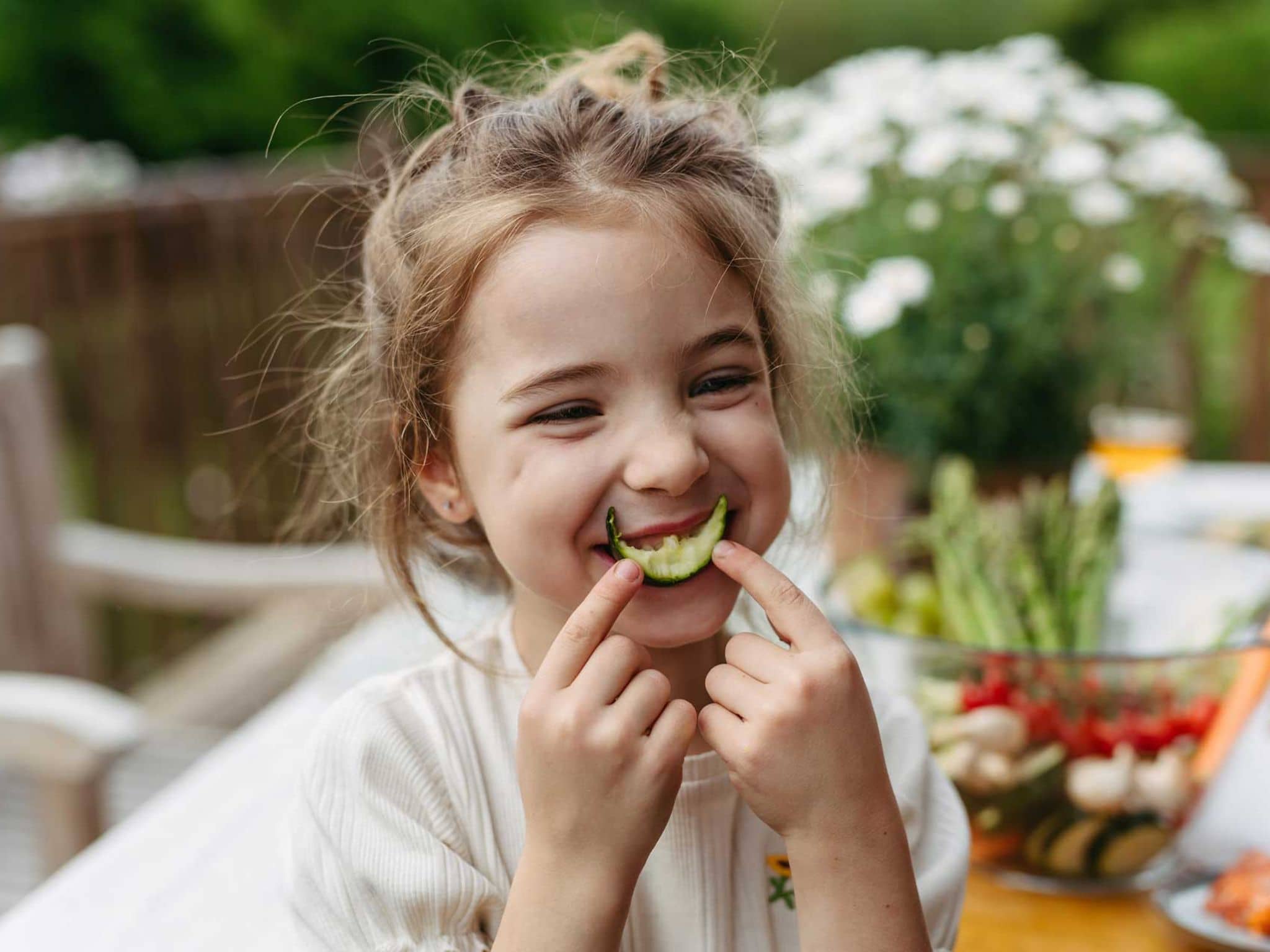 Mädchen hält sich angebissene Gurke vor den Mund