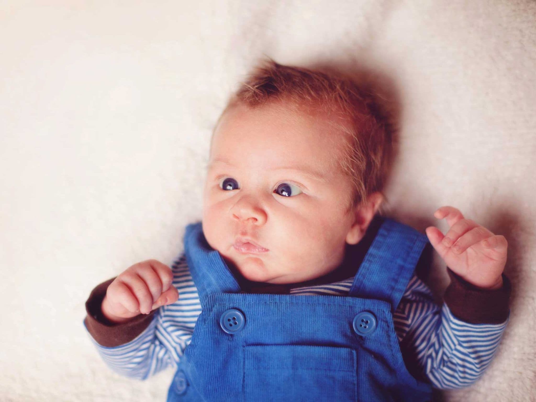 Ein schielendes Baby liegt im Bett