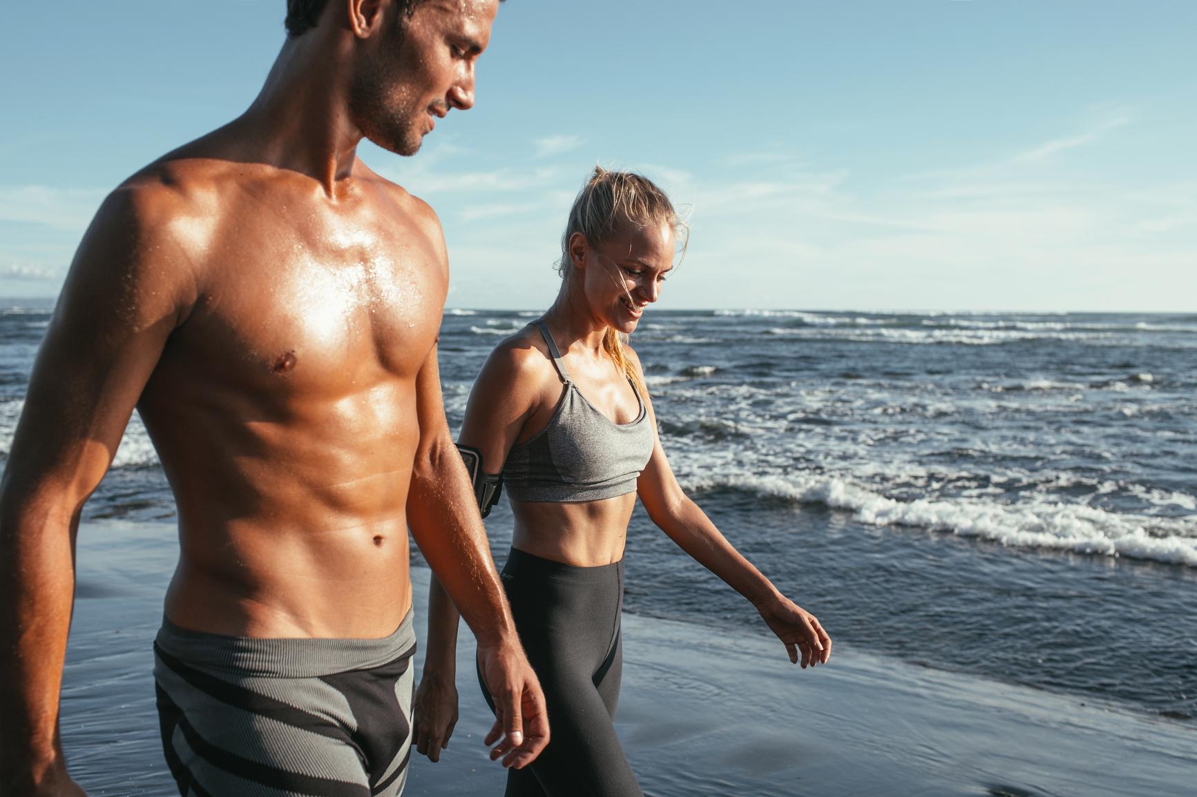 Körperfett: Mann und Frau gehen an einem Sommertag am Strand spazieren