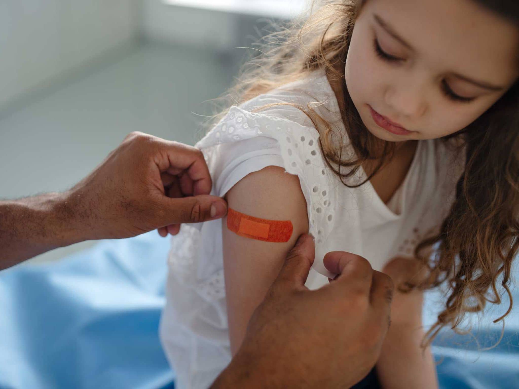 Mädchen wird Pflaster auf den Oberarm geklebt
