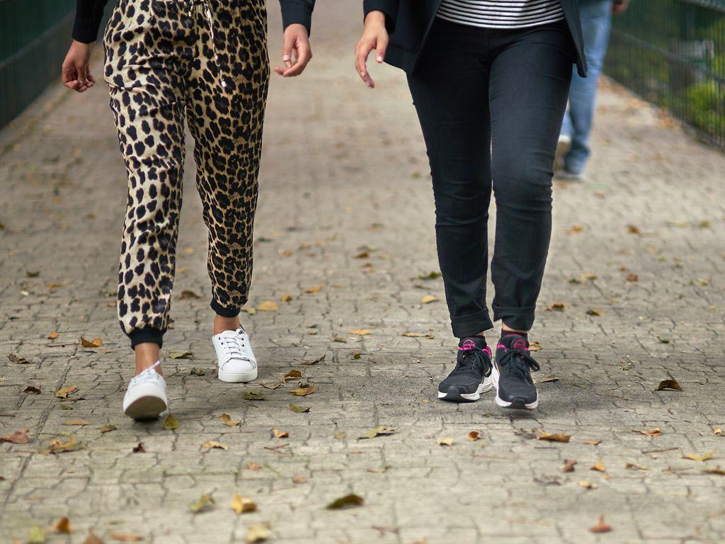 Schritte pro Tag: Ausschnitt der Beine zweier Menschen, die nebeneinander laufen