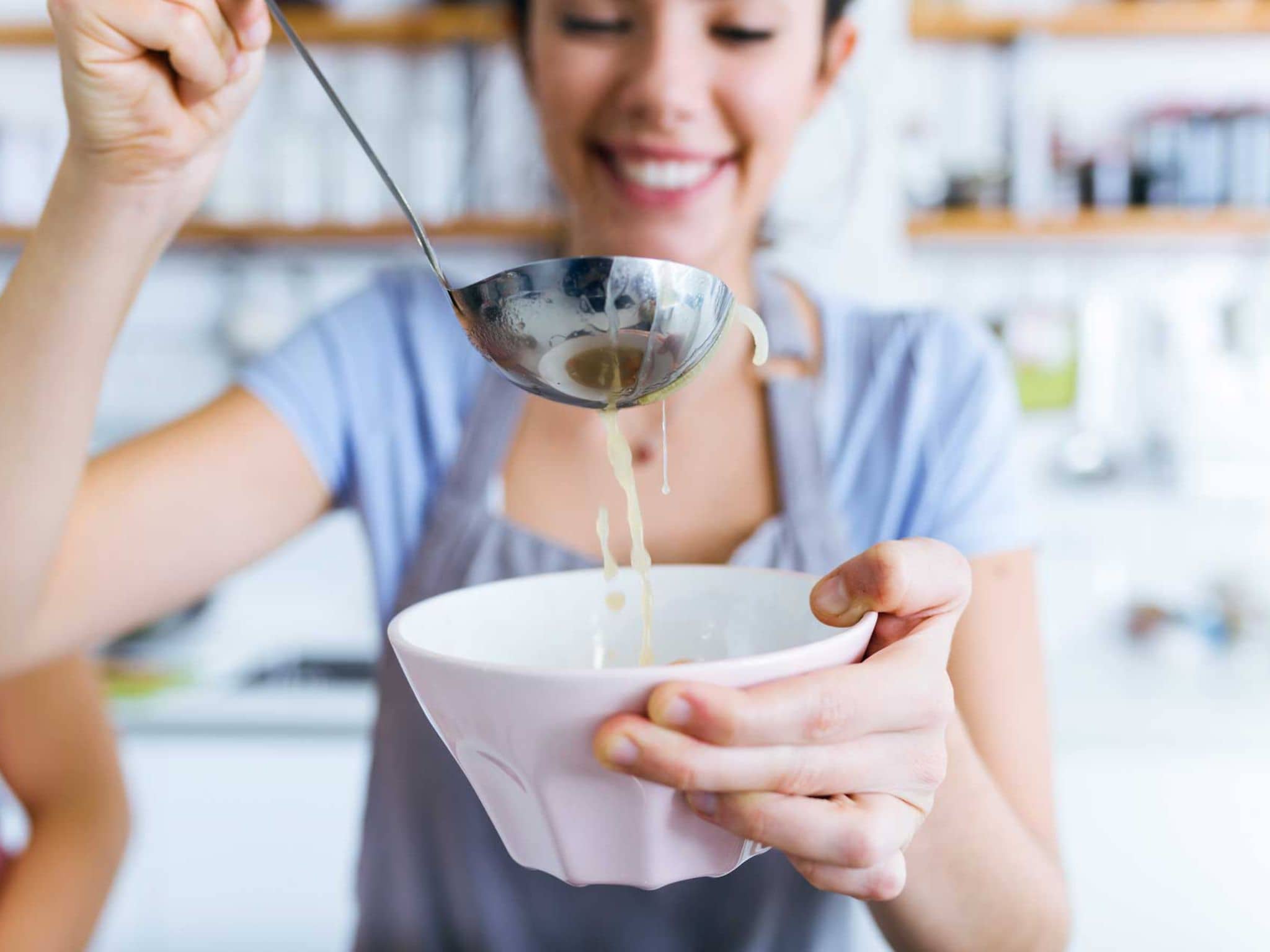 Frau füllt Suppe in eine Schüssel
