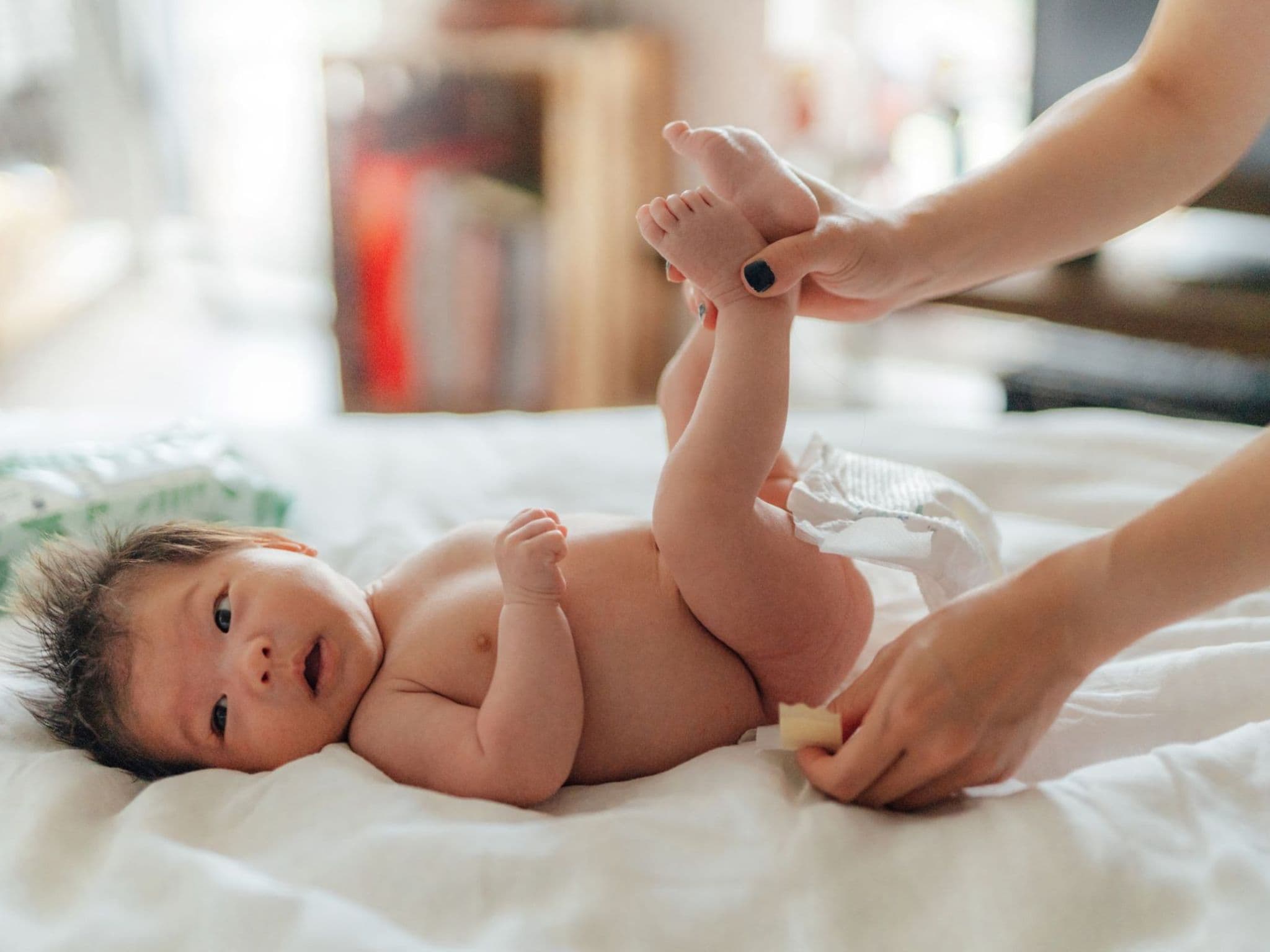 Eine Mutter wechselt die Windeln ihres Babys – ein Weg gegen Windeldermatitis.