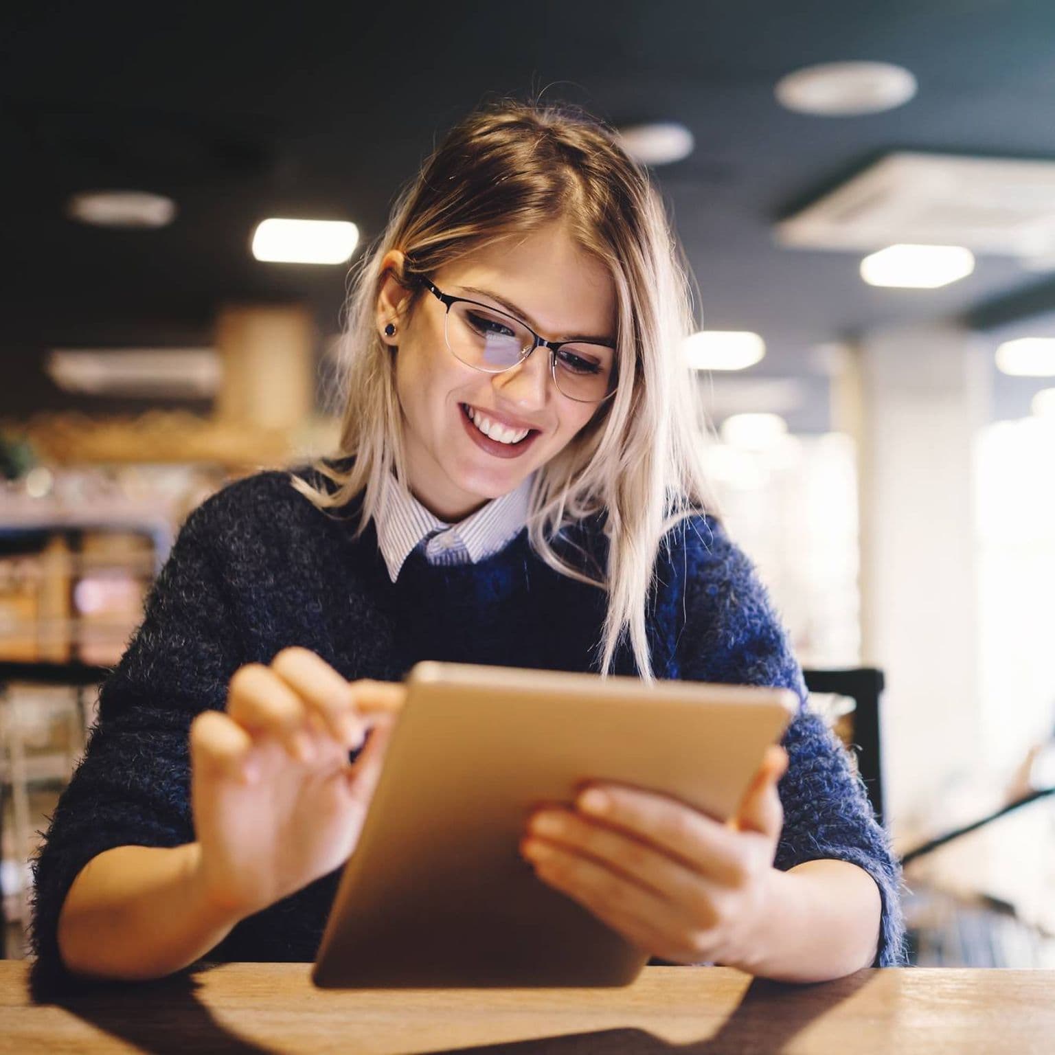 Bild: Junge Frau lächelt während sie sich auf dem Tablet die Angebote der DAK anschaut.