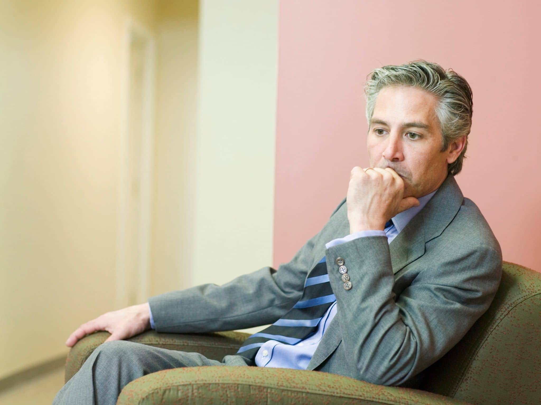 Posttraumatische Belastungsstörung: Ein älterer Herr im Anzug sitzt in einem Sexel und guckt traurig-depressiv