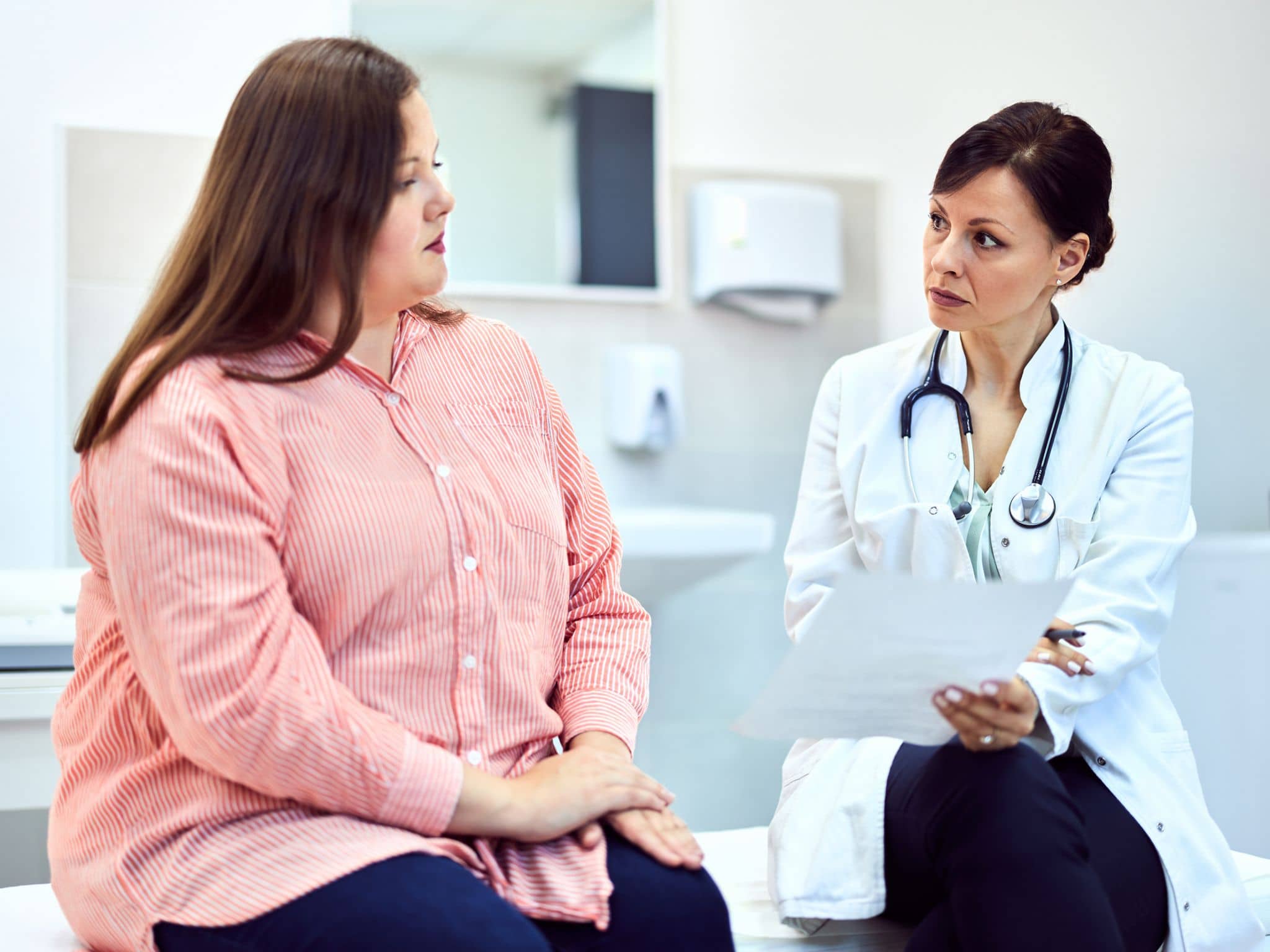 Lipödem-OP: Eine Frau mit Lipödem sitzt mit einer Ärztin im Behandlungsraum eines Krankenhauses