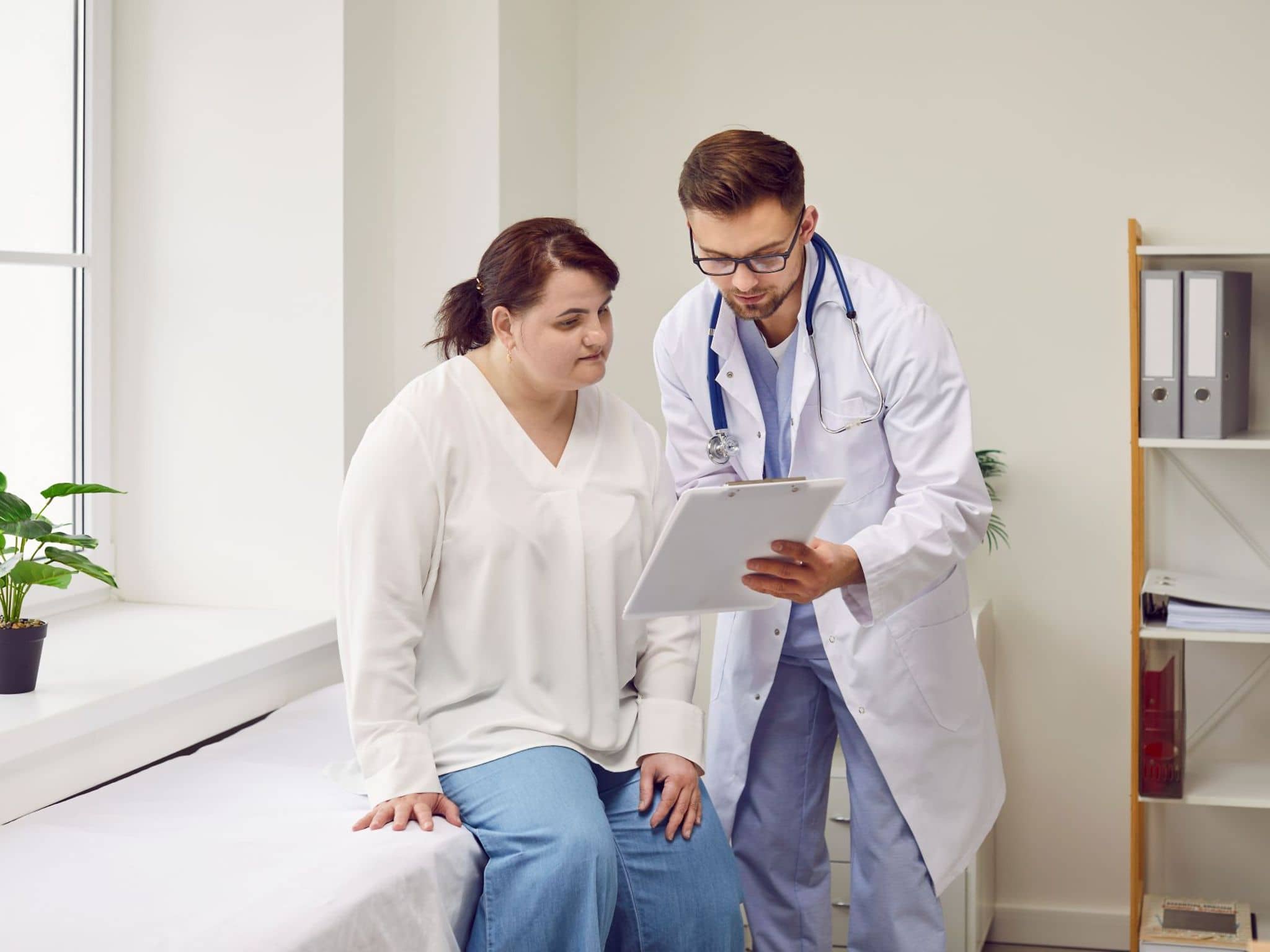 Ein Arzt spricht im Rahmen der Nachsorge nach einer bariatrischen OP mit einer Patientin.