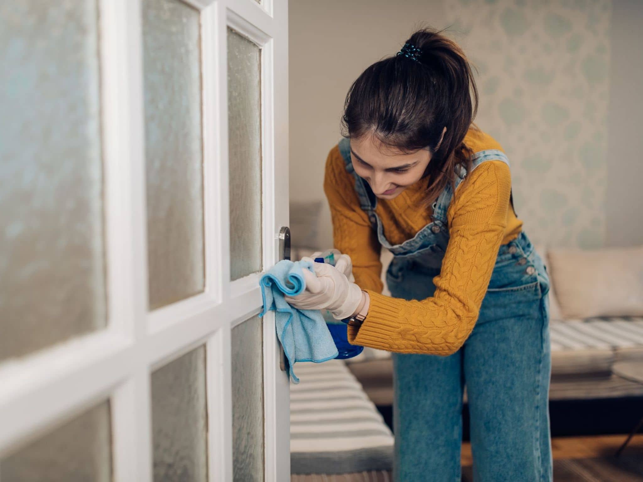 Eine Frau macht eine Türklinke sauber, um einer Erkältung vorzubeugen.