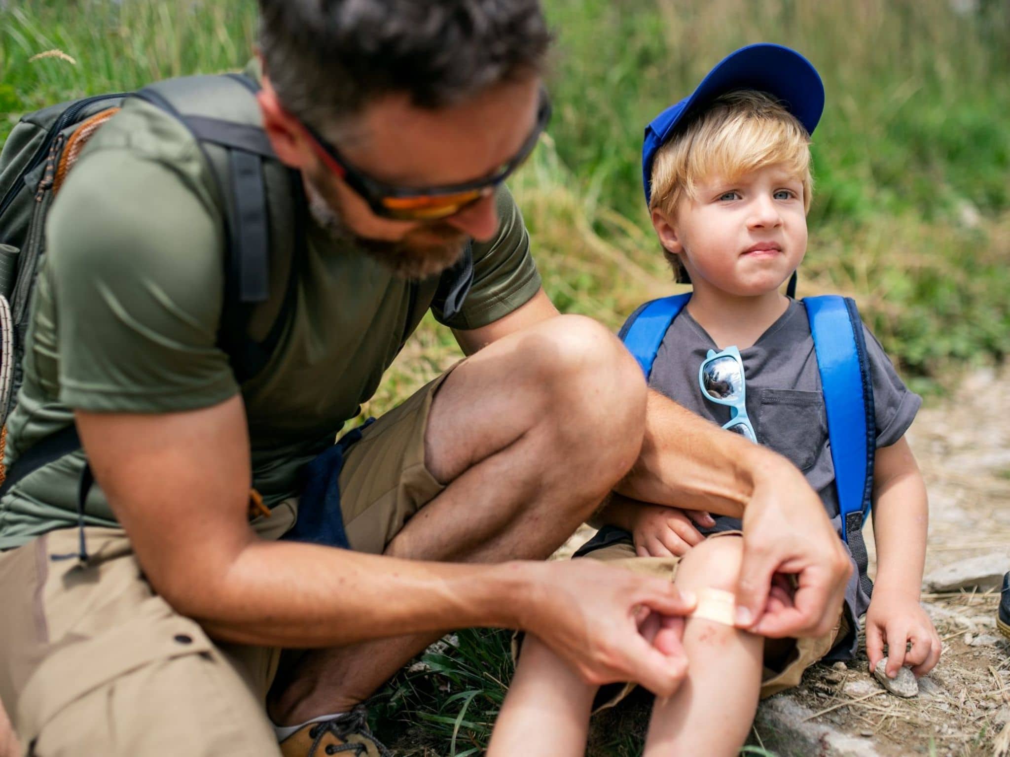 Ein Vater klebt seinem Sohn ein Pflaster aufs Knie.
