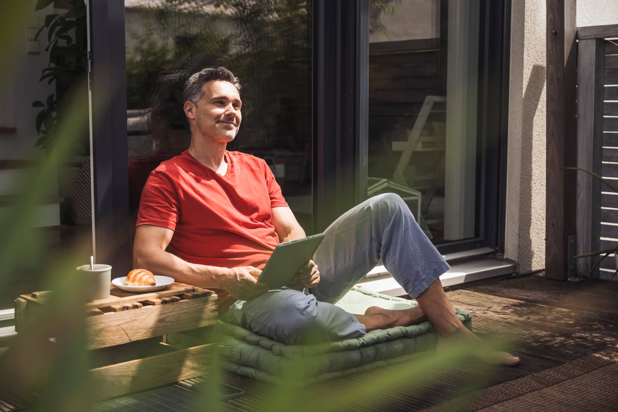 DAK Garantietraif 150: Mann sitzt entspannt auf Terrasse mit Tablet