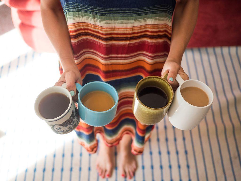 Koffein: Frau hält vier verschiedene Tassen Kaffee in den Händen