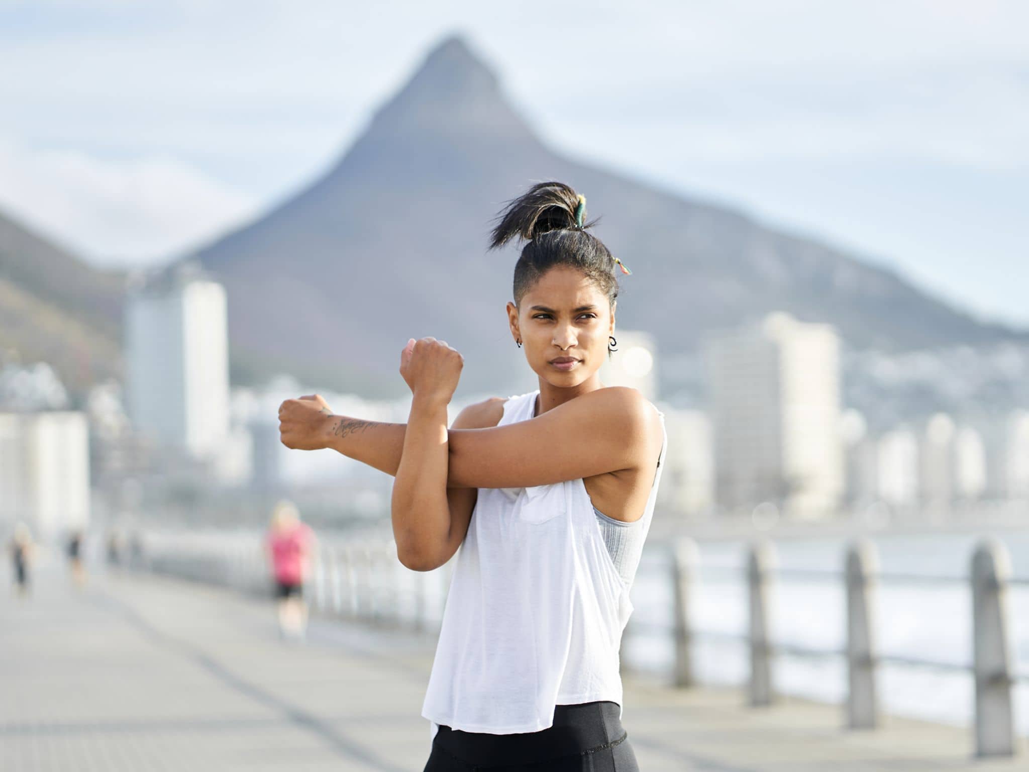 Eine junge Frau dehnt sich während eines Workouts auf einem städtischen Gehweg