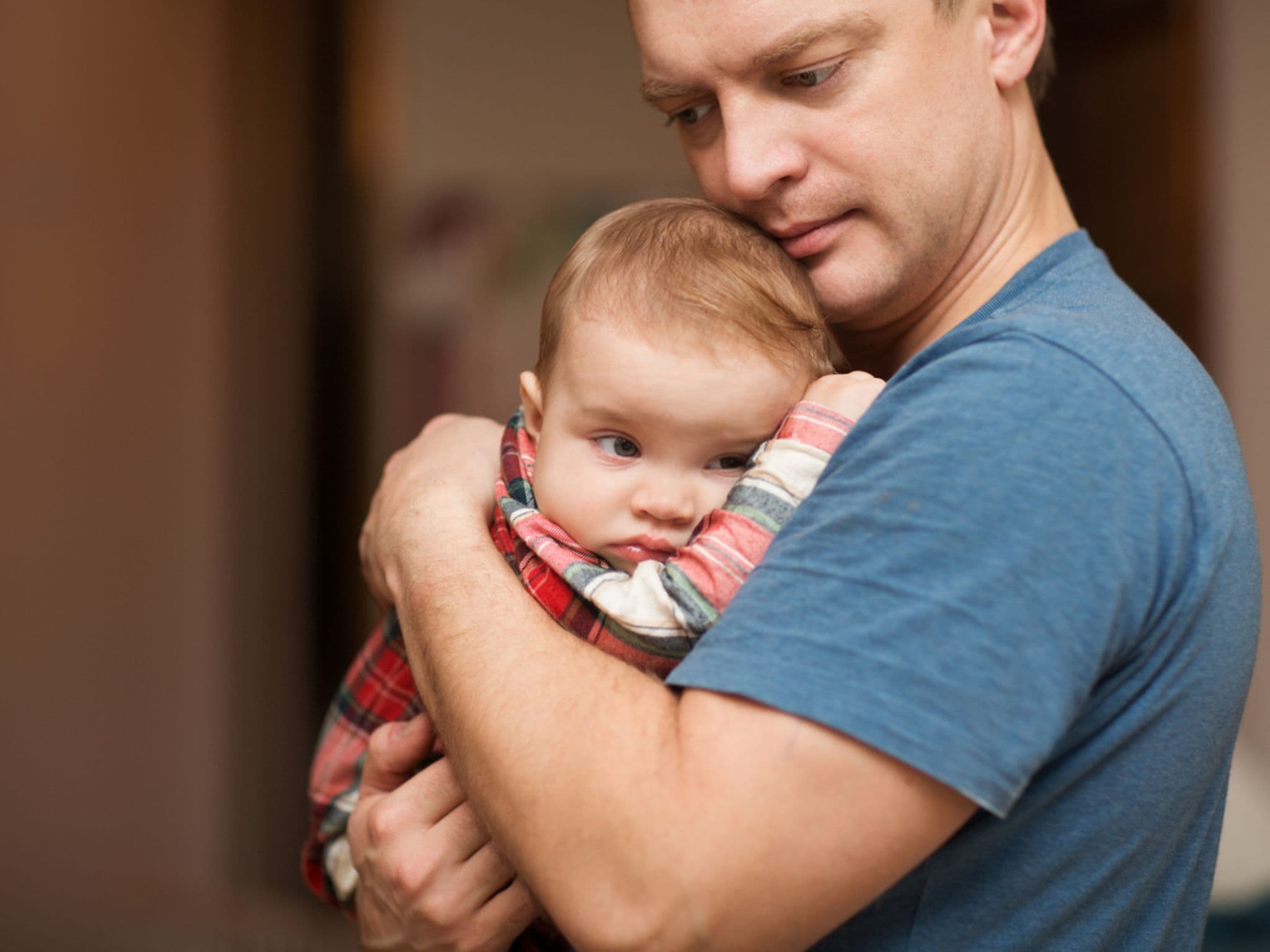 Der Vater hält auf den Händen der traurige Baby. Familien-Konzept. Auf die Milchzähne werden geschnitten.