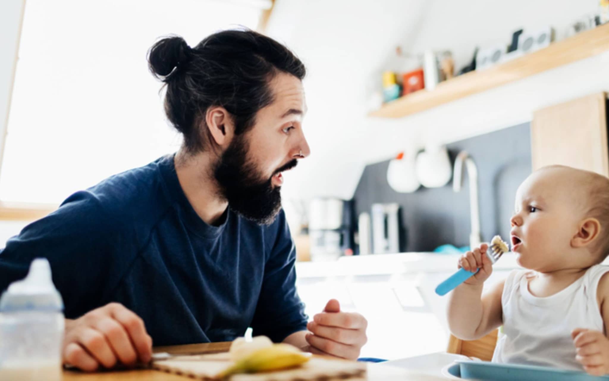 Gesunder Ernährung Kinder: Ein Vater bereitet seinem kleinen Kind eine Banane zum Essen vor.