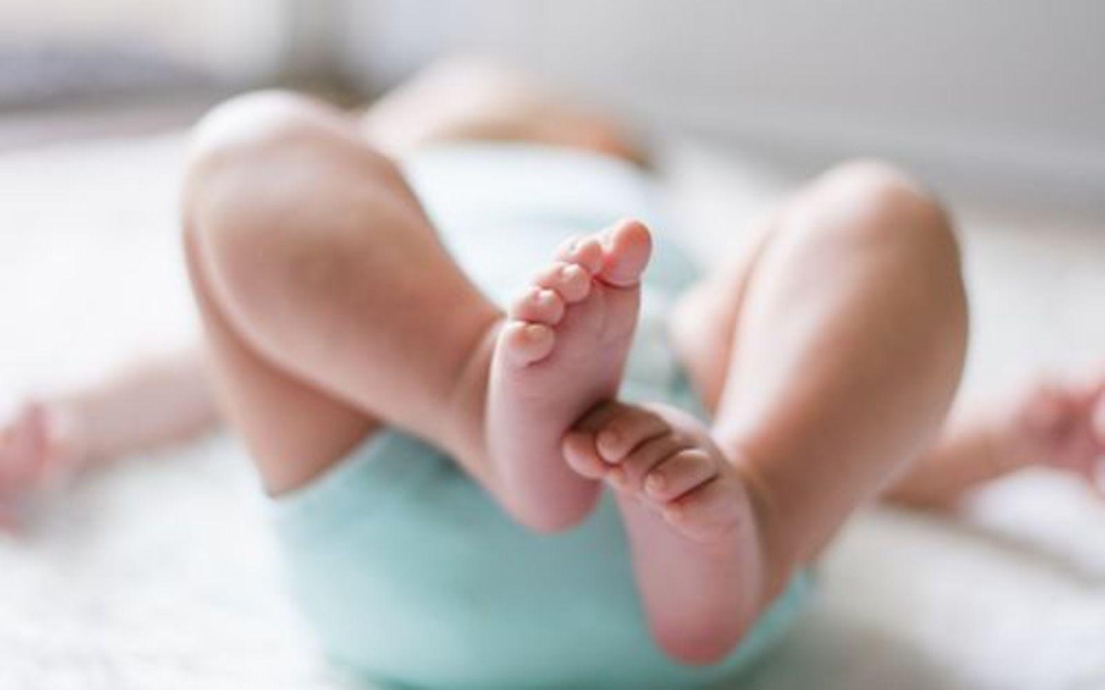 Symbolbild Babypflege: Ein Baby streckt seine Füße in die Luft, Ansicht von unten