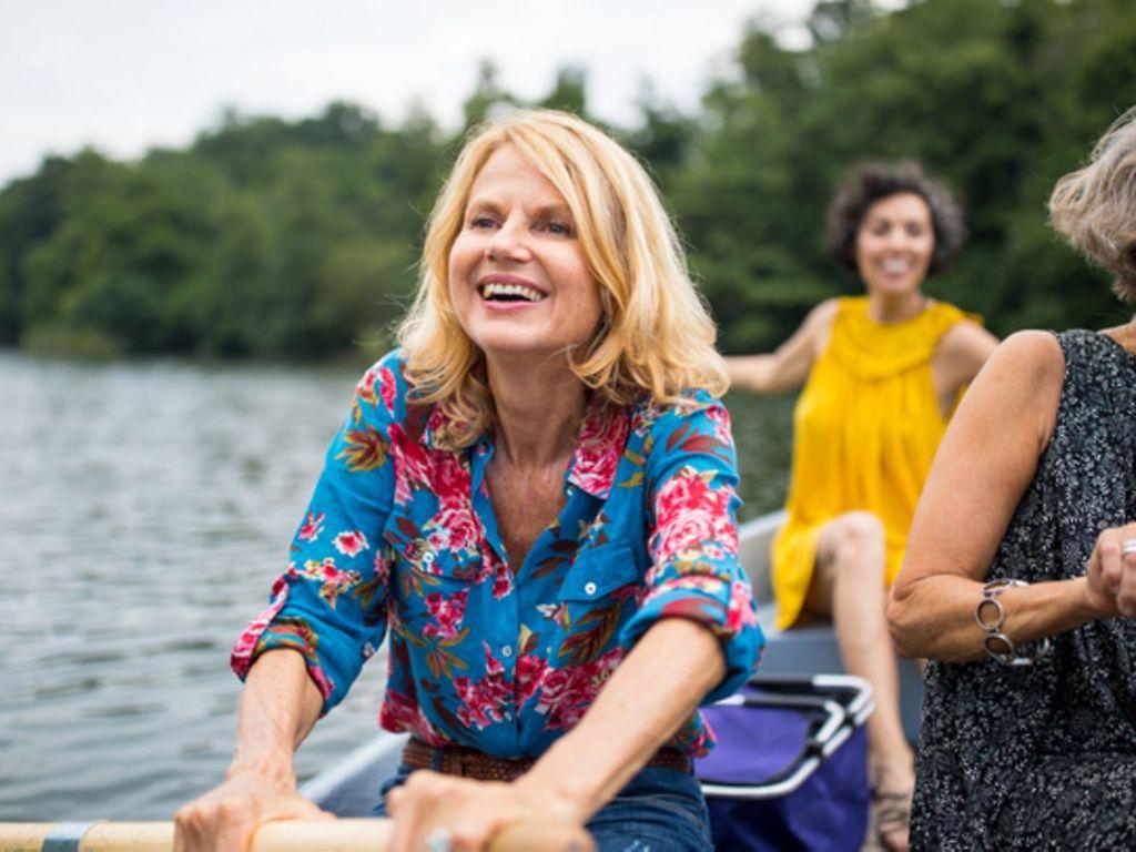 Lächelnde Frau mit Freund-Ruderboot in See