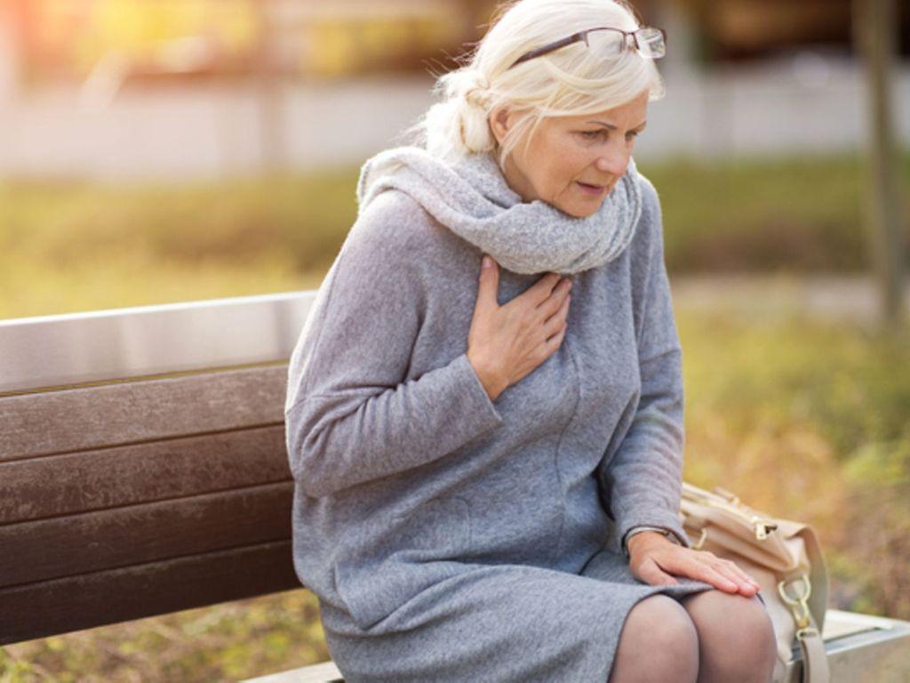 Lungenembolie: Ältere Dame sitzt auf einer Parkbank und ringt nach Luft