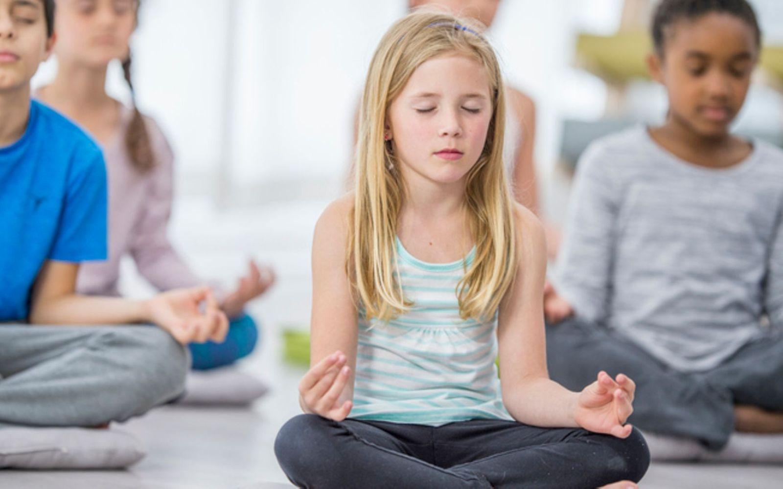 Achtsamkeit: Eine Gruppe Kinder sitzt auf dem Boden und meditiert.