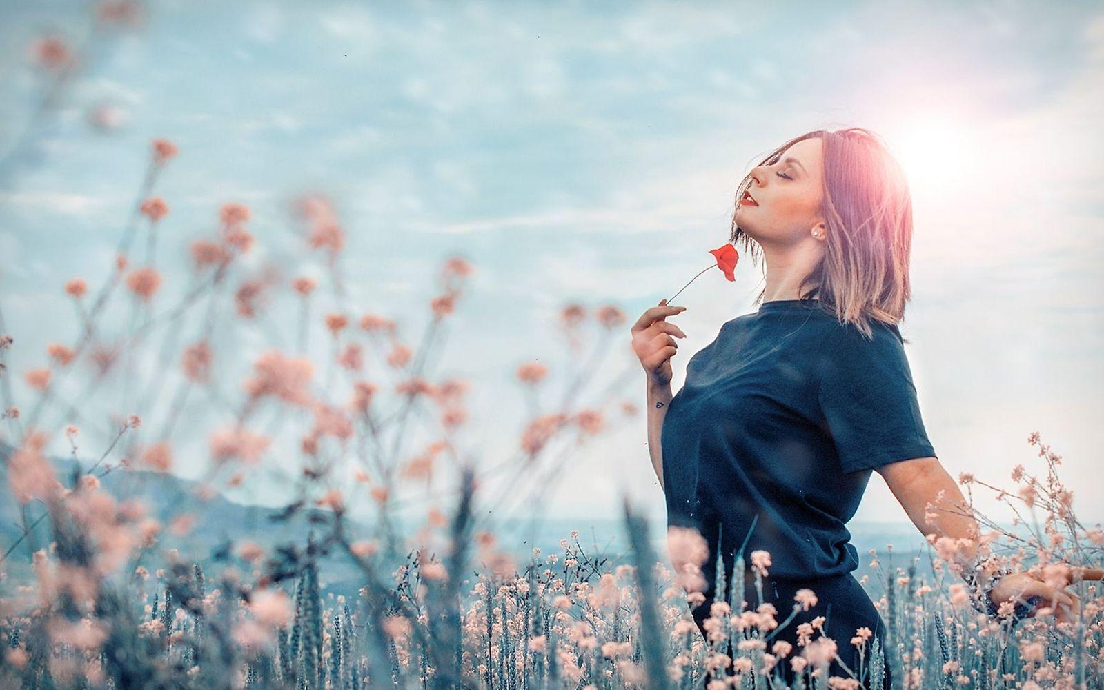Sinnlichkeit: Eine Frau riecht an Blumen und genießt das Leben.