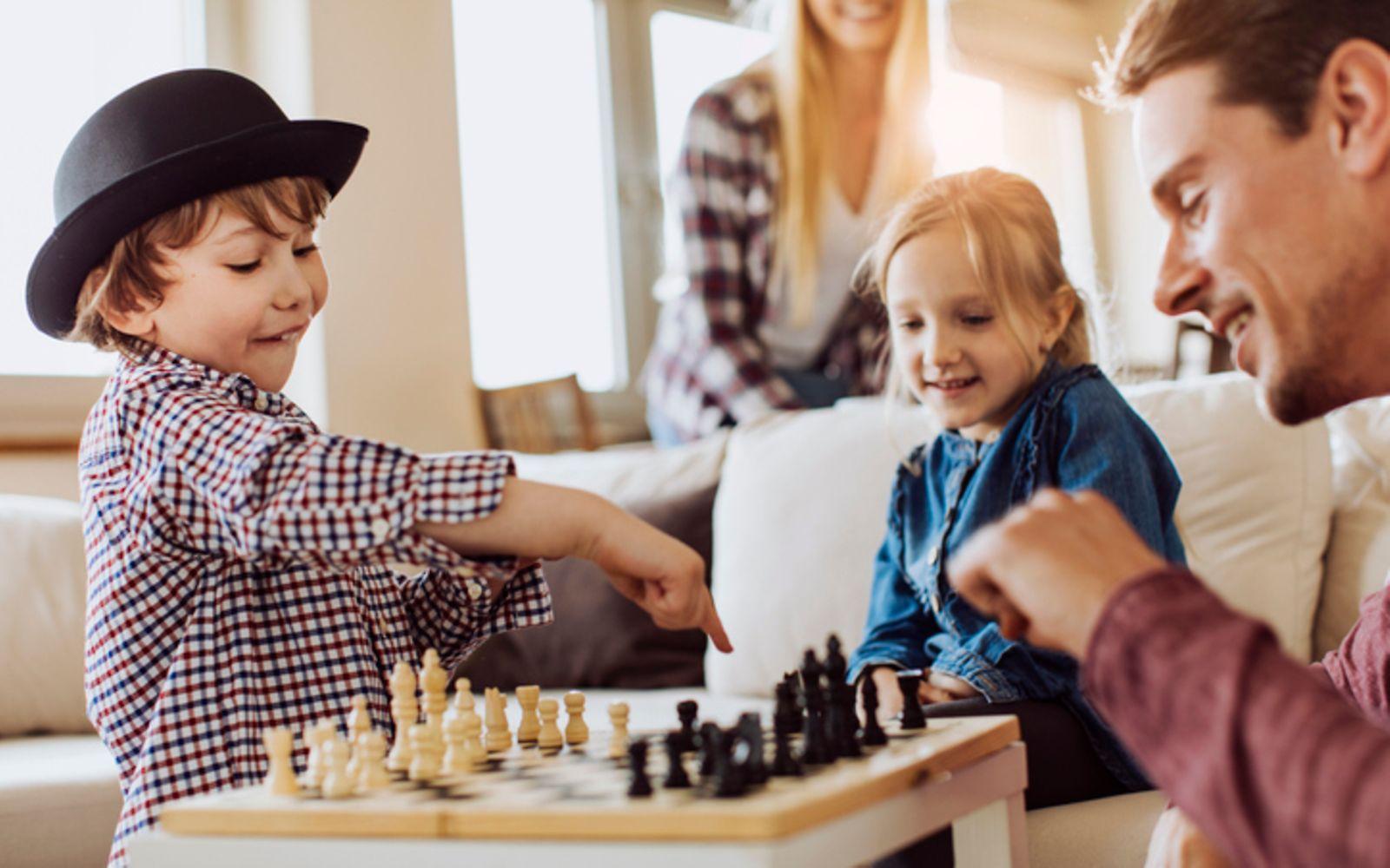 Schach fürs Gehirn: Zwei Kinder spielen mit ihrem Vater Schach.