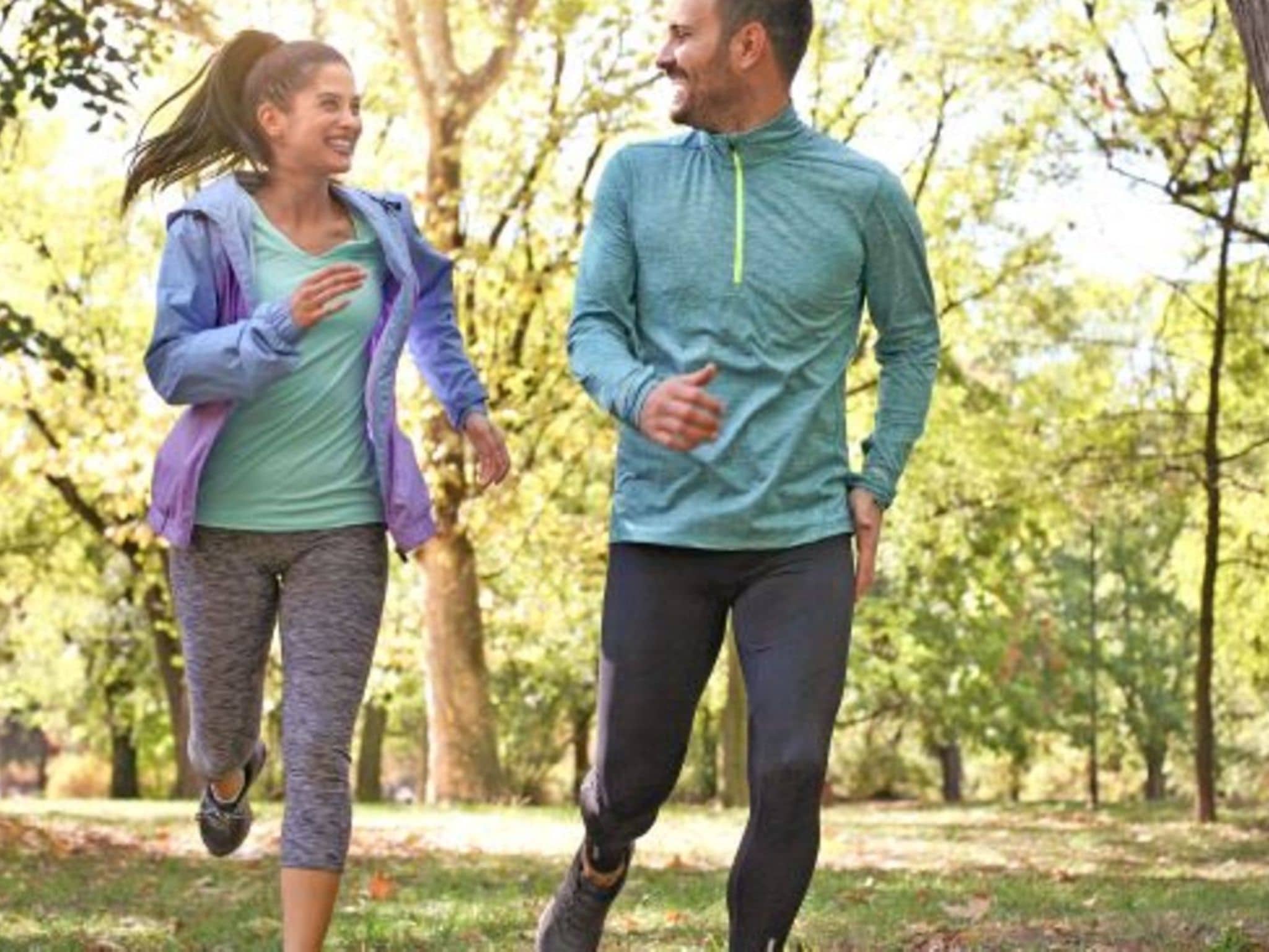 Fit im Frühling: Ein Mann und eine Frau joggen durch den Wald.