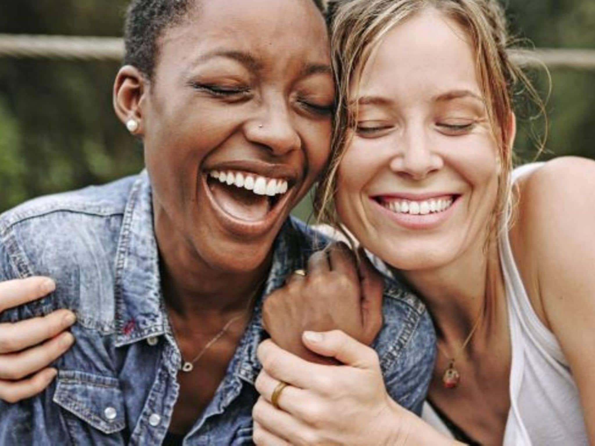 Zwei Frauen, die sich in den Arm nehmen und gemeinsam lachen.