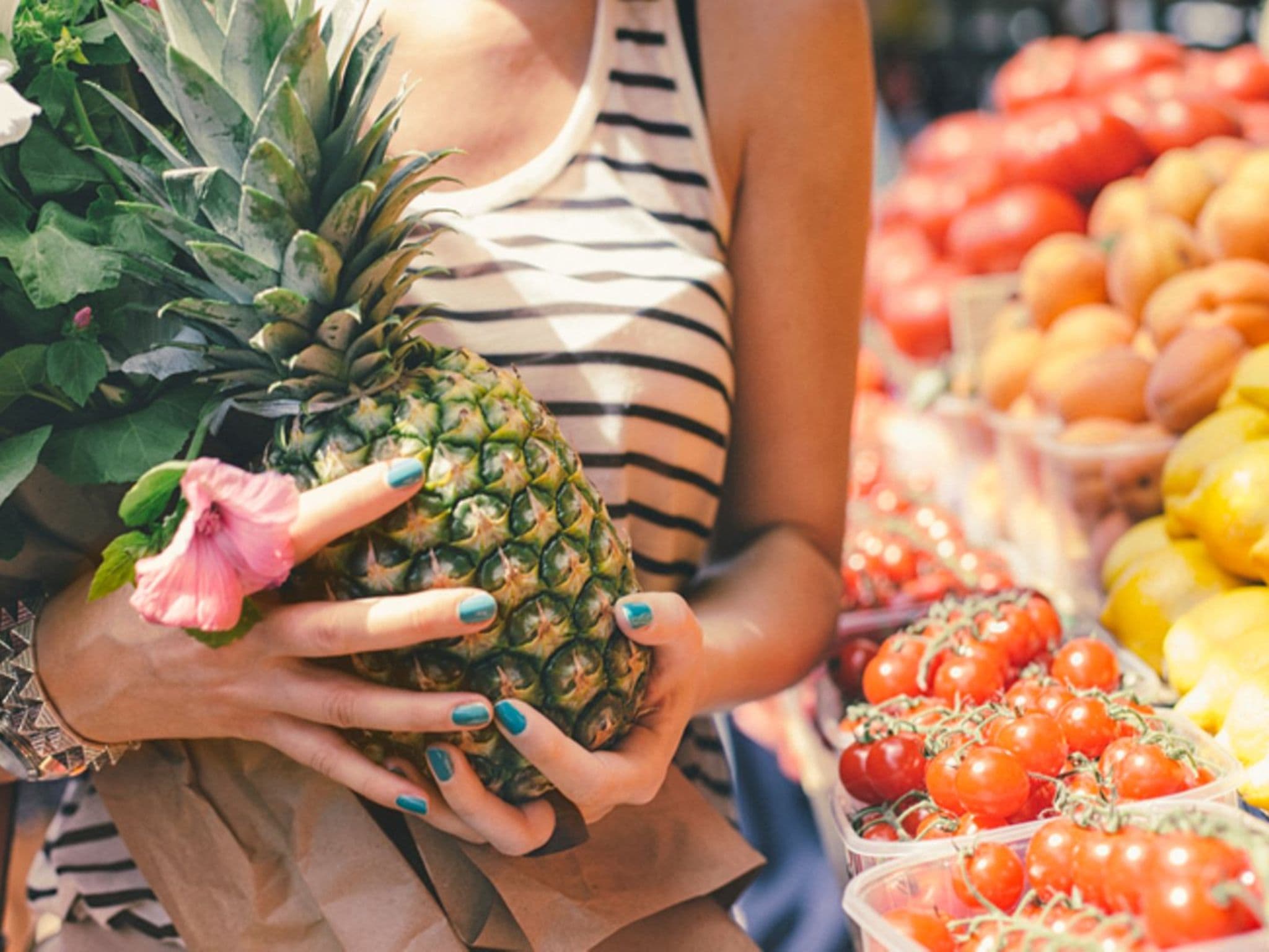Vegane Ernährung: Frau hat auf einem Wochenmarkt eine Ananas gekauft.